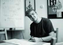 Zdjęcie przedstawia mężczyznę, który siedzi przy biurku i rysuje