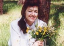 Zdjęcie przedstawia autorkę tomiku trzymającą w dłoni bukiet kwiatów.