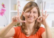 Zdjęcie ukazuje kobietę pokazującą na dłoniach znaki w języku migowym.